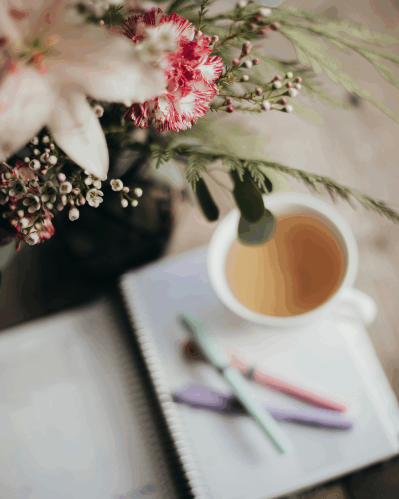 des fleurs, un chocolat chaud et des stylo pour travailler efficacement en tant que copywriter SEO à Toulouse